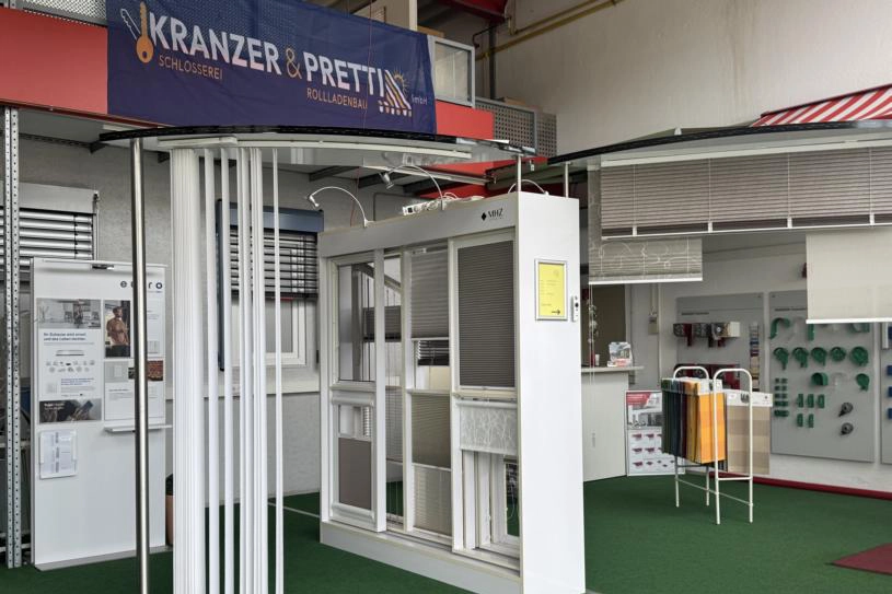 Banner mit Logo der Firma Kranzer & Pretti über Teilen ihrer Ausstellung mit Vertikaljalousie