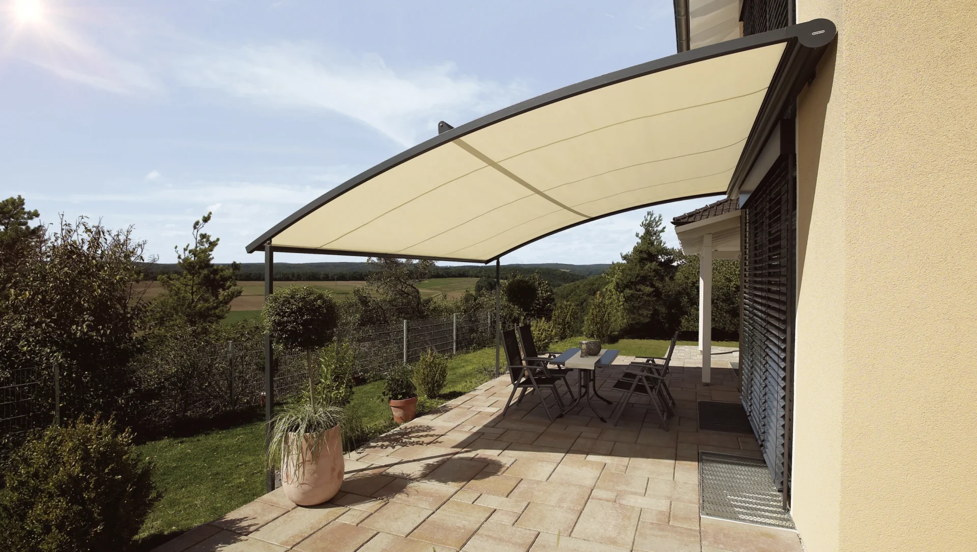 Moderne Terrassenüberdachung mit stilvollen Möbeln bei Sonnenschein